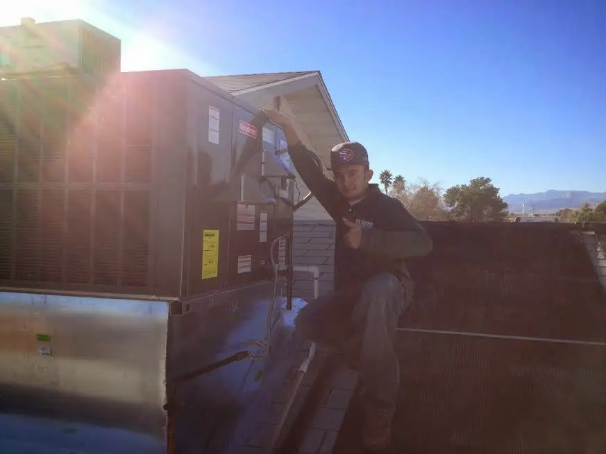HVAC technician performing Air Duct Cleaning on a rooftop unit in Watsonville